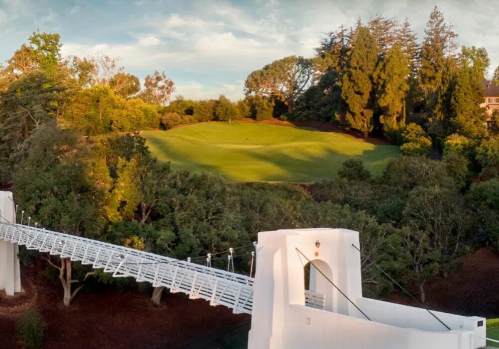 A golf course green surrounded by autumn trees under a cloudy sky.